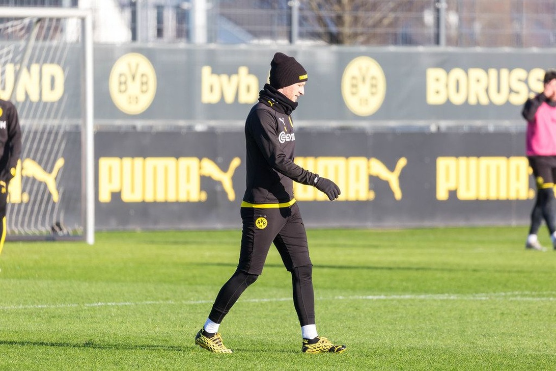 En professionell fotbollsspelare från Borussia Dortmund med full vinterutrustning inklusive mössa och handskar.